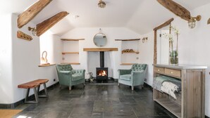 A cozy living room with a fireplace, two armchairs, a wooden bench, and a small table. - Harbour Cottage (Boscastle)