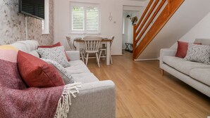 A spacious living area with a dining table, sofas, and a staircase. - Hunters Cottage (High Peak)