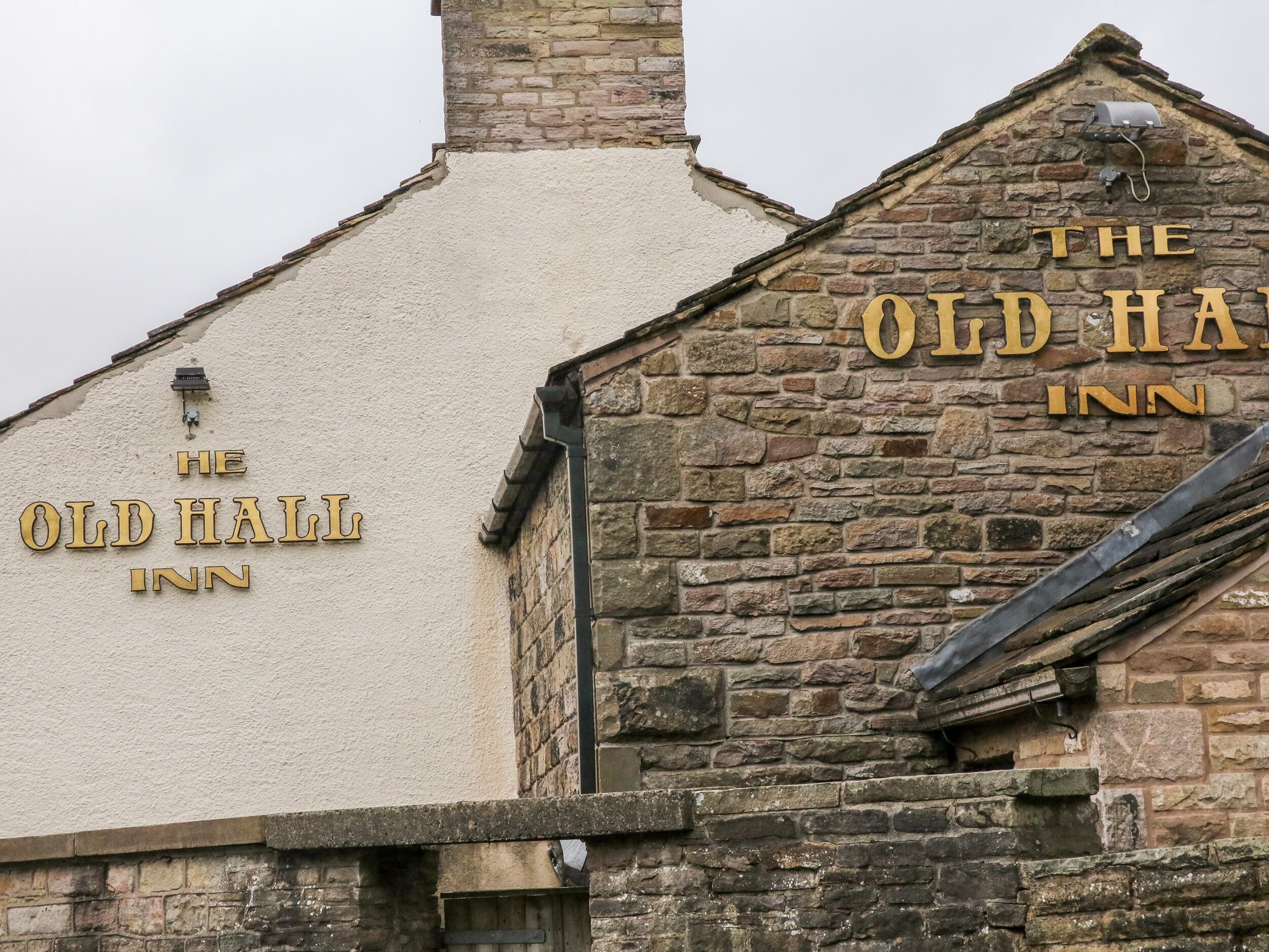 A building with the sign "The Old Hall Inn" on a stone wall.