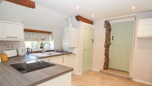 Una cucina moderna con piano cottura integrato, mobili bianchi e una porta verde chiaro.