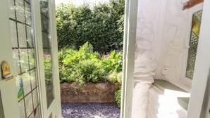 Un'apertura che dà su un giardino con muro in pietra e vegetazione.
