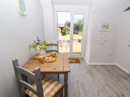 Un comedor con una mesa de madera, sillas, un jarrón con flores y un plato de comida.
