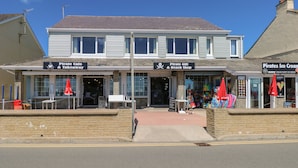 Een gebouw met twee verdiepingen met een bord waarop 'Pirate Cafe & Takeaway' en 'Pirate Gift & Beach Shop' staat.