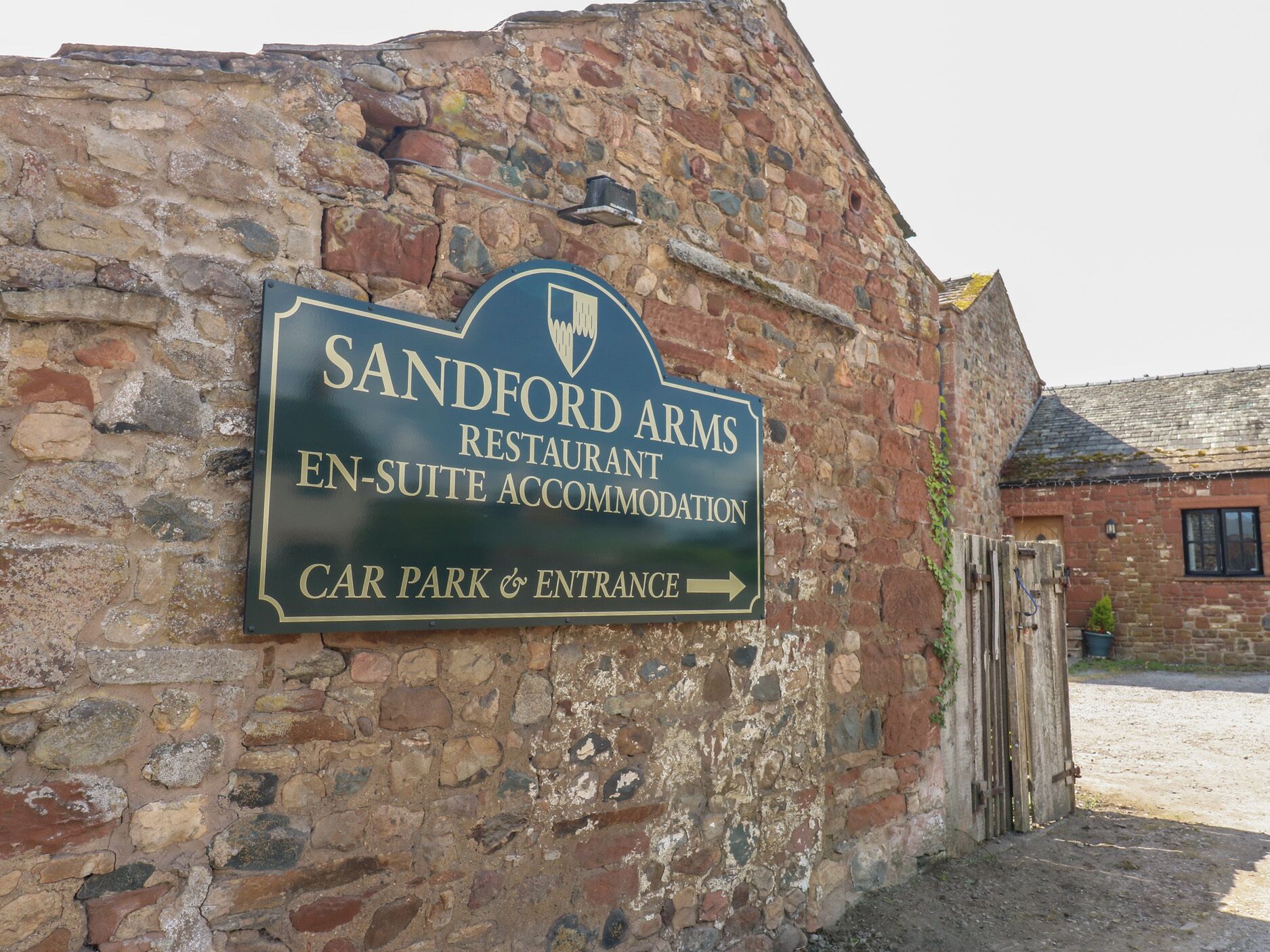 A sign for Sandford Arms Restaurant and En-Suite Accommodation with a direction to the car park and entrance.