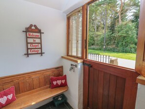 A wooden bench with a cushion, a welcome sign, a window with blinds, and a gate. - Chapel Cottage (Appleby-in-Westmorland)