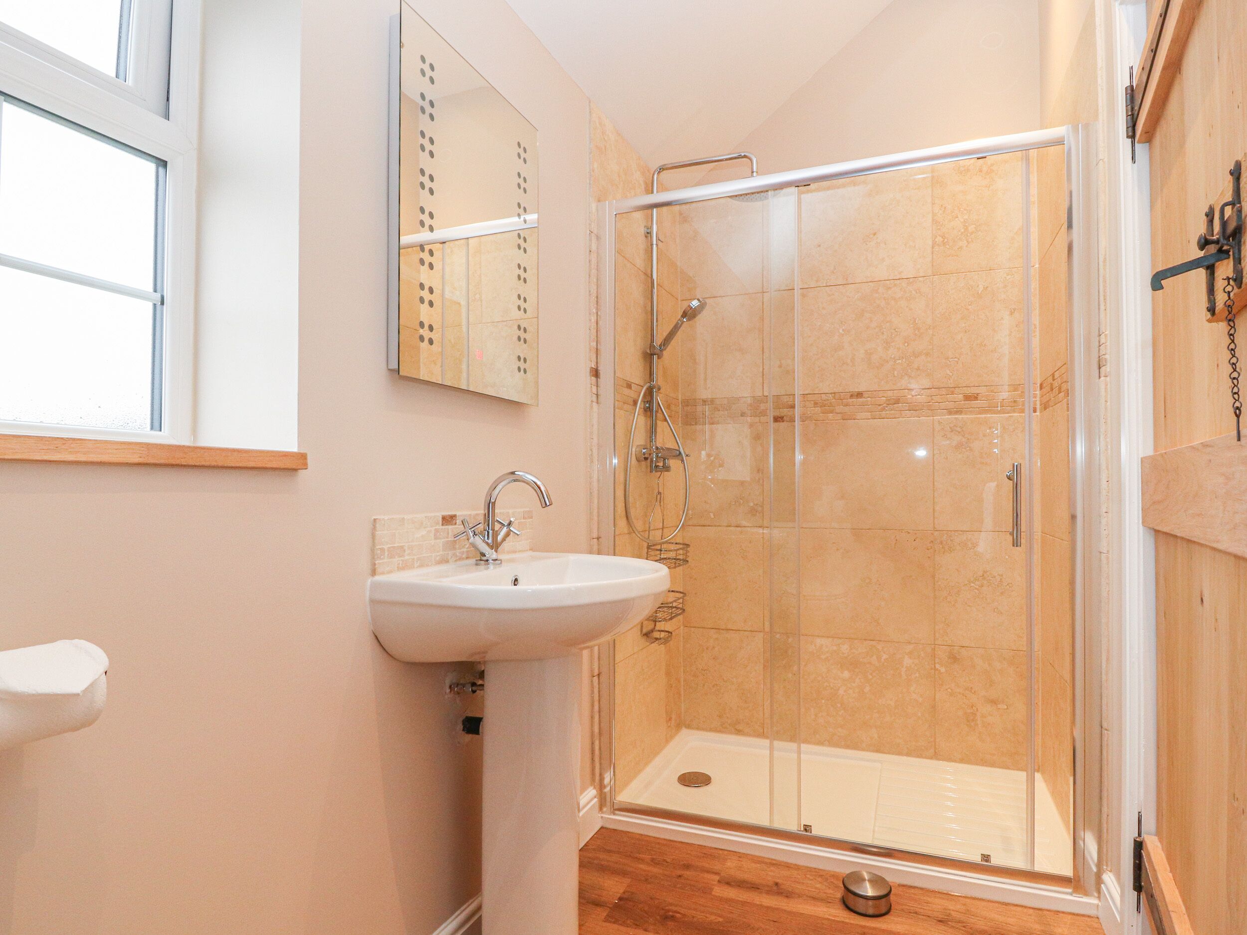 Une salle de bain avec une douche à parois de verre, un lavabo et un miroir.