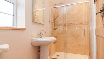 Une salle de bain avec une douche à parois de verre, un lavabo et un miroir.