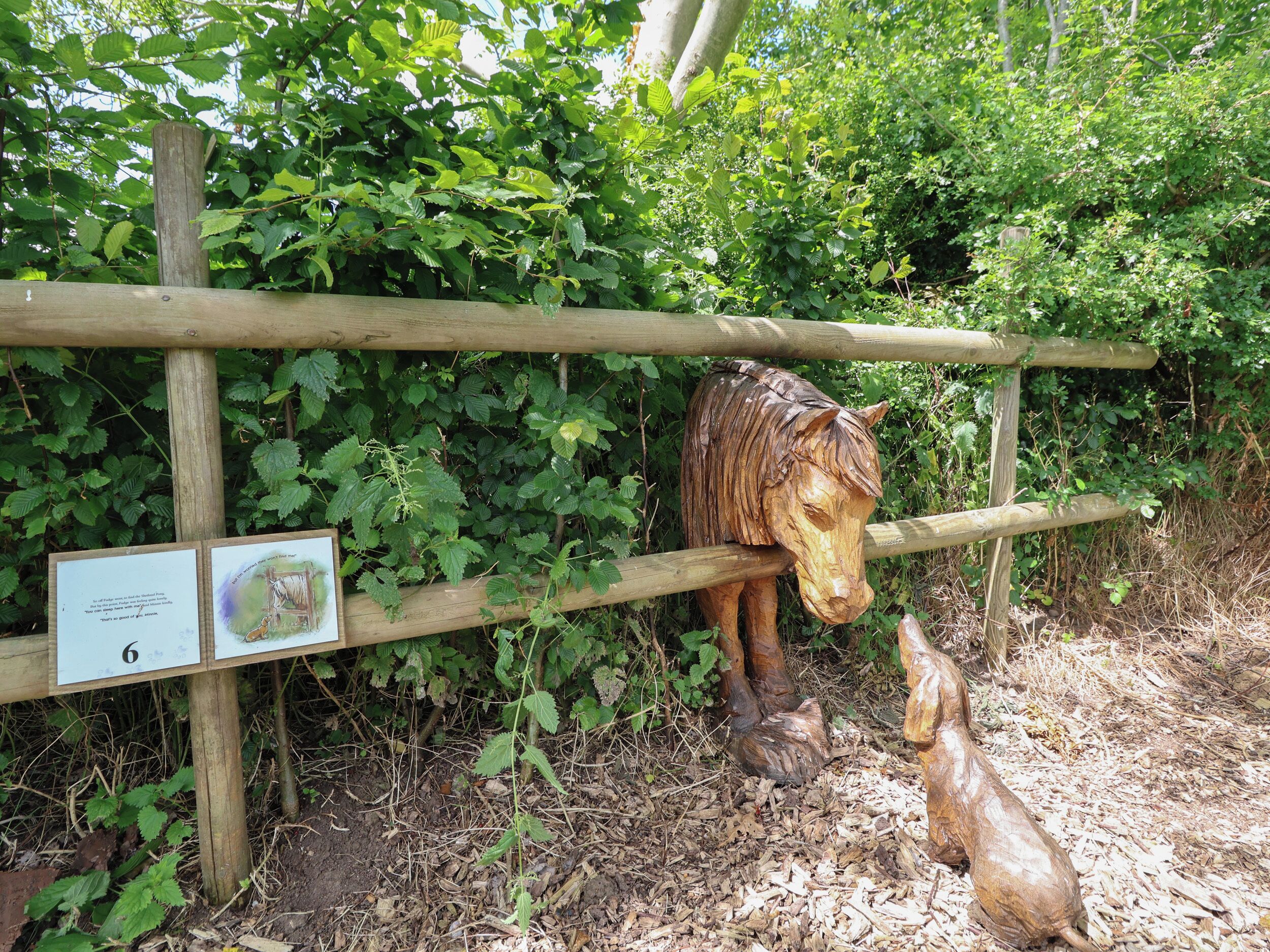 Une clôture en bois ornée d’une sculpture de cheval et d’un panneau.