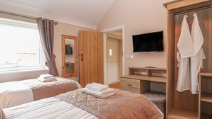 A hotel room with two beds, a wooden wardrobe, a TV, and a bathroom door. - The Shippon (Chester)