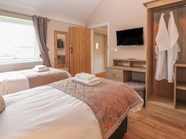 A hotel room with two beds, a wooden wardrobe, a TV, and a bathroom door.