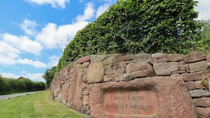Un mur de pierres sur lequel est apposée une pancarte indiquant : « Location de cottages à la ferme de Lower Farm ».