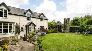 A house with a well-maintained garden, a gazebo, and outdoor seating. - Eleri Cottage (Malvern)