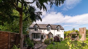 A two-story house with a garden, a wooden fence, and a shed. - Eleri Cottage (Malvern)