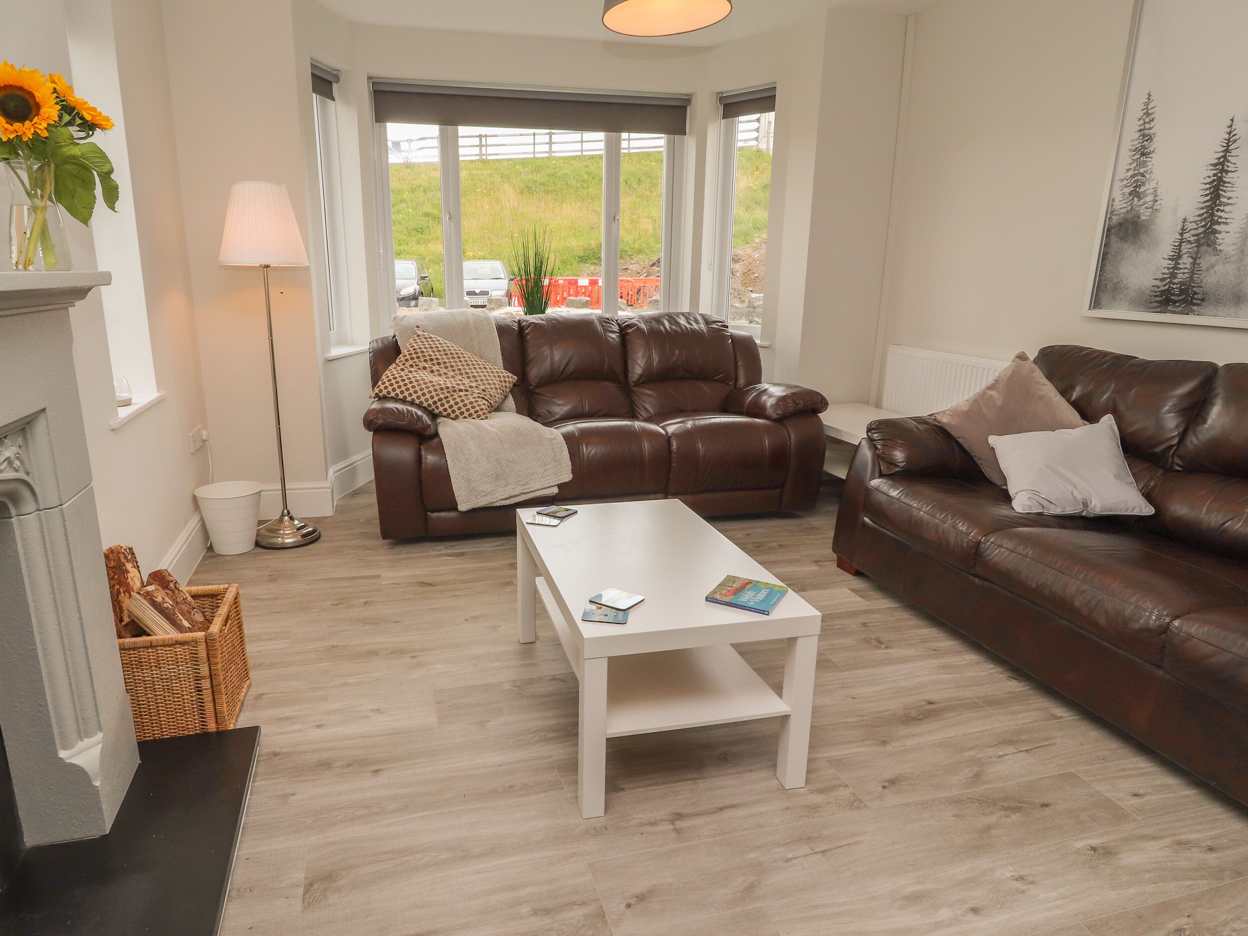 A living room with two brown leather sofas, a white coffee table, and a fireplace.