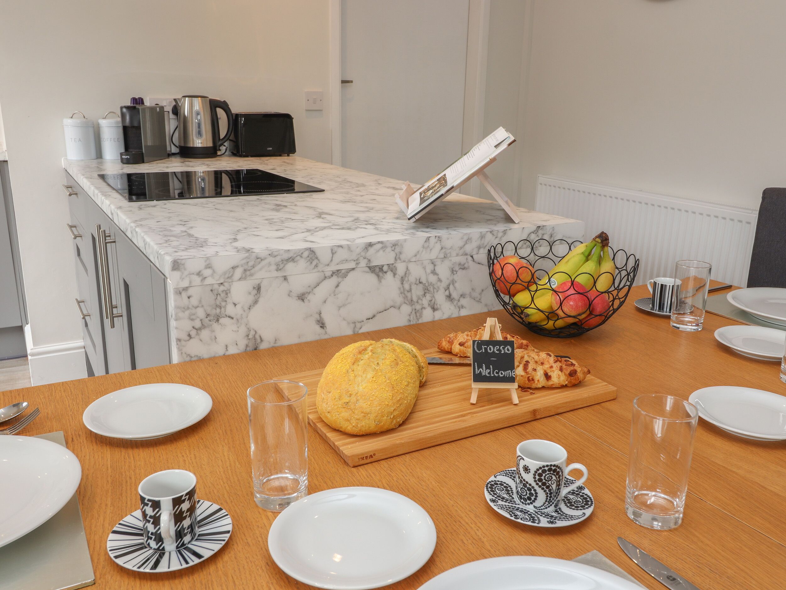 A breakfast setup with croissants, a fruit bowl, and a coffee station.