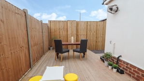 A wooden deck with a table and chairs, surrounded by a wooden fence.