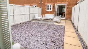 A backyard with a patio area, white outdoor furniture, and a white fence. - 5 Styleman Road (Hunstanton)