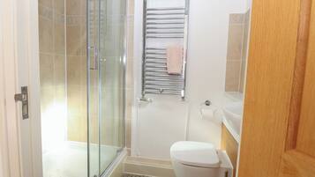 A bathroom with a glass shower enclosure, a white toilet, and a towel rack with a pink towel.
