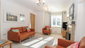 A living room with a brown sofa, a smaller armchair, a wooden coffee table, and a fireplace. - 5 Styleman Road (Hunstanton)