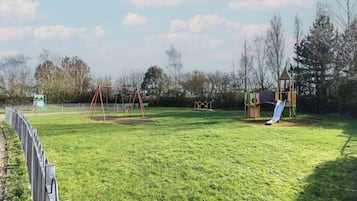 Un parque infantil con columpios, un tobogán y una estructura para escalar.