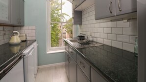 A kitchen with grey cabinets, a window, and a view of the outside. - Belvedere (Buxton)