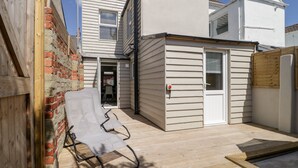 Een overdekt terras met een houten dek, een overdekte zithoek en een kleine schuur.