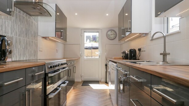 Een moderne keuken met roestvrijstalen apparatuur, houten aanrechtbladen en een visgraatvloer.