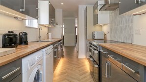 Een moderne keuken met roestvrijstalen apparatuur, houten aanrechtbladen en een visgraatvloer.