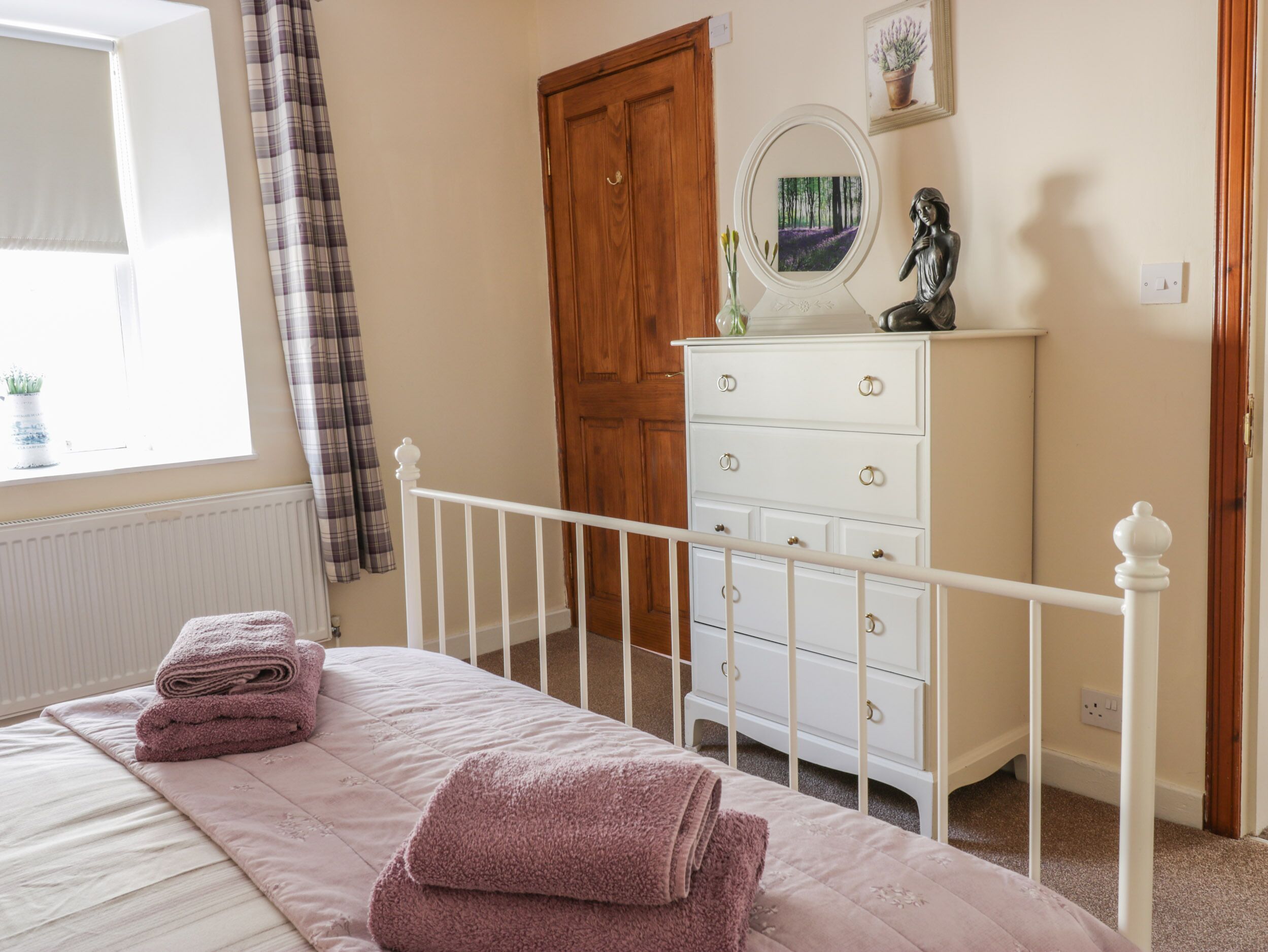 A bedroom with a bed, a dresser, a mirror, and a door.
