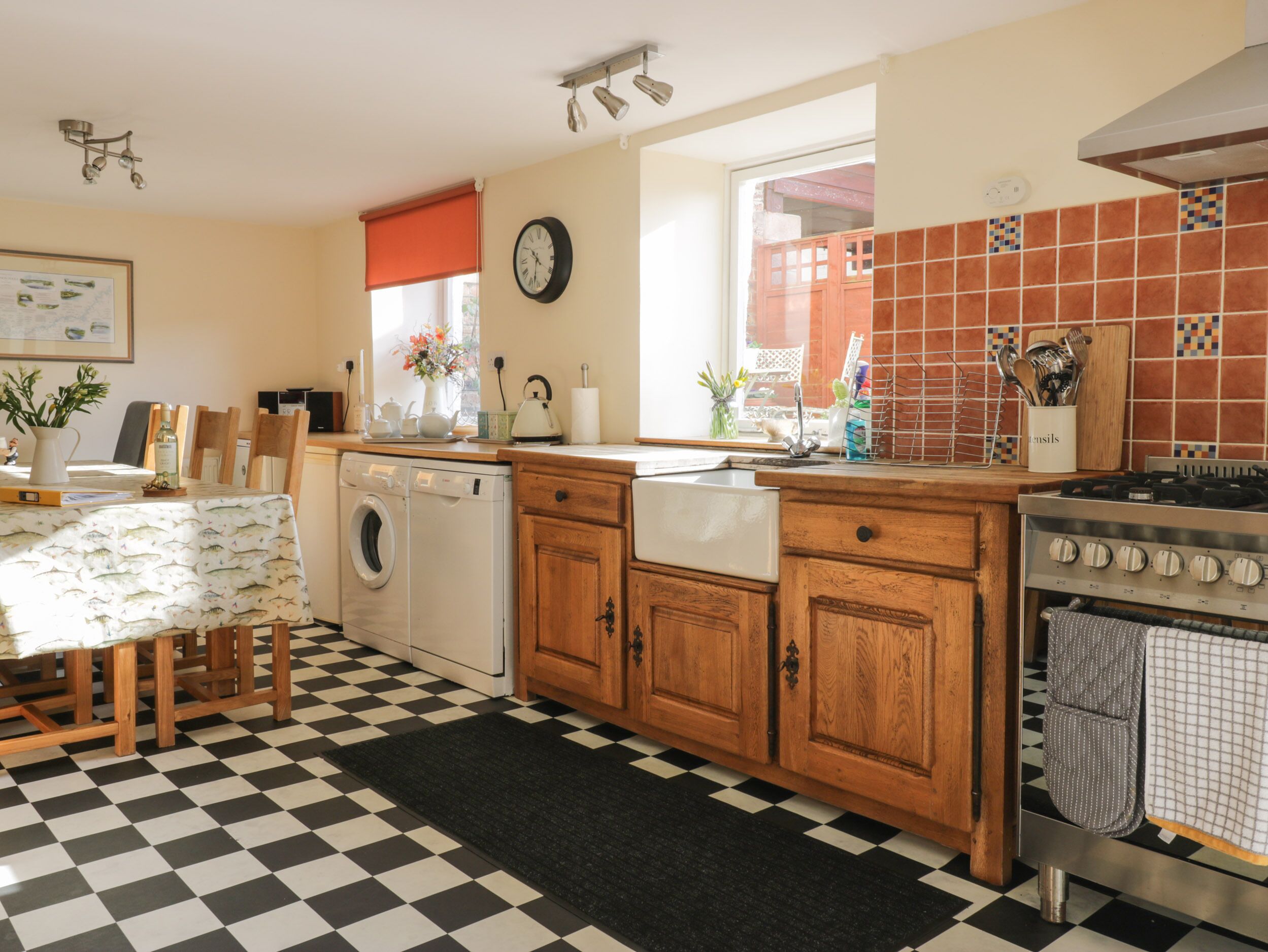 A kitchen with a washing machine, wooden cabinets, a stove, and a checkered floor.