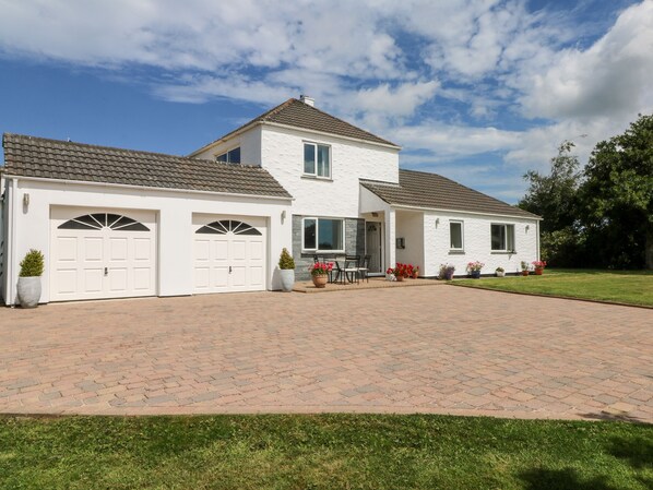 A two-story house with a paved driveway and a well-maintained lawn. - Trevore Farmhouse (Truro)