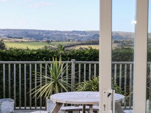 A balcony with a view of a rural landscape, a round table, and a potted plant. - Trevore Farmhouse (Truro)