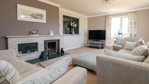 A living room with a fireplace, a television, and a sofa set. - Trevore Farmhouse (Truro)
