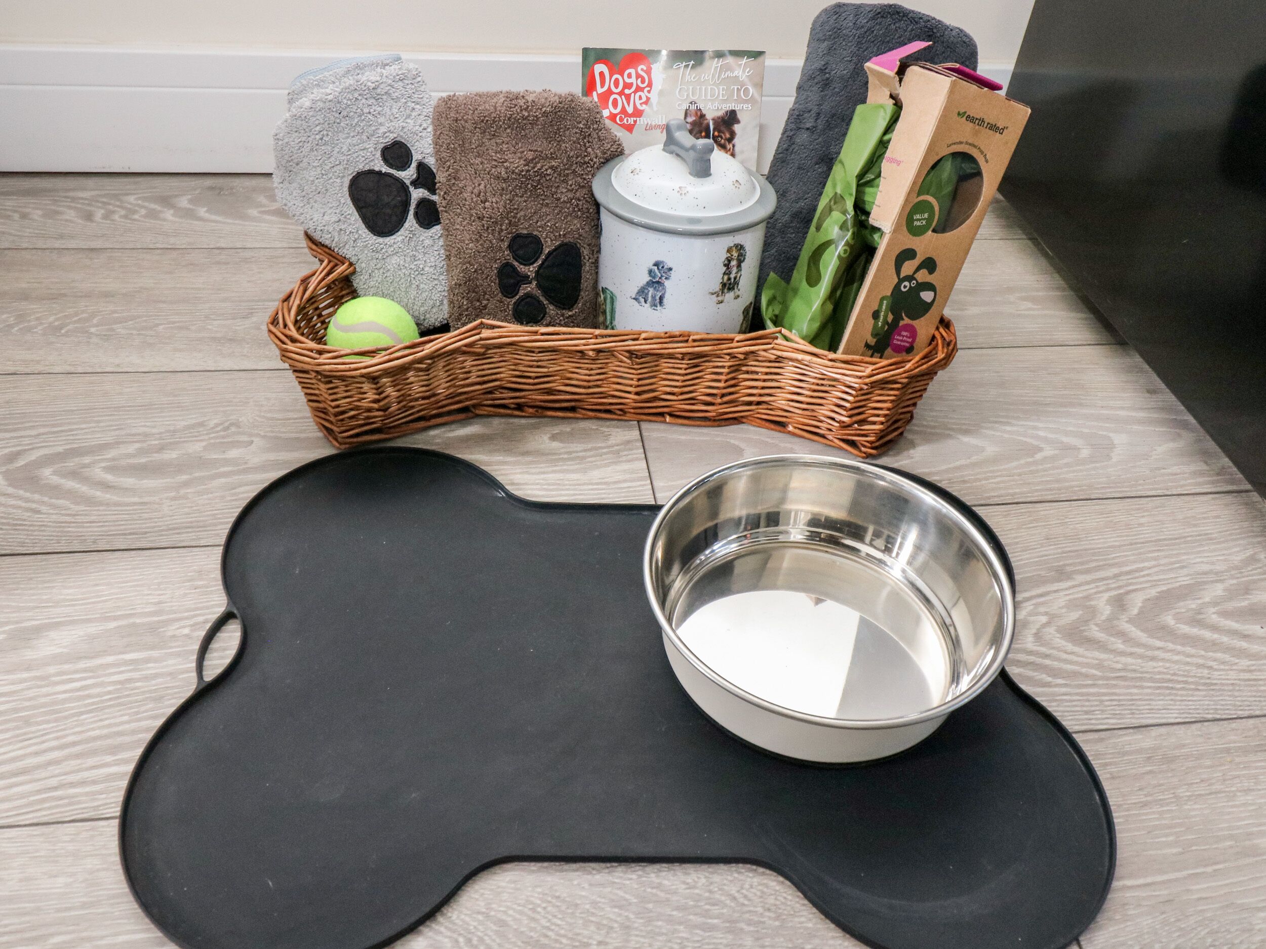 A pet care setup with a basket containing pet supplies, a bowl, and a mat.