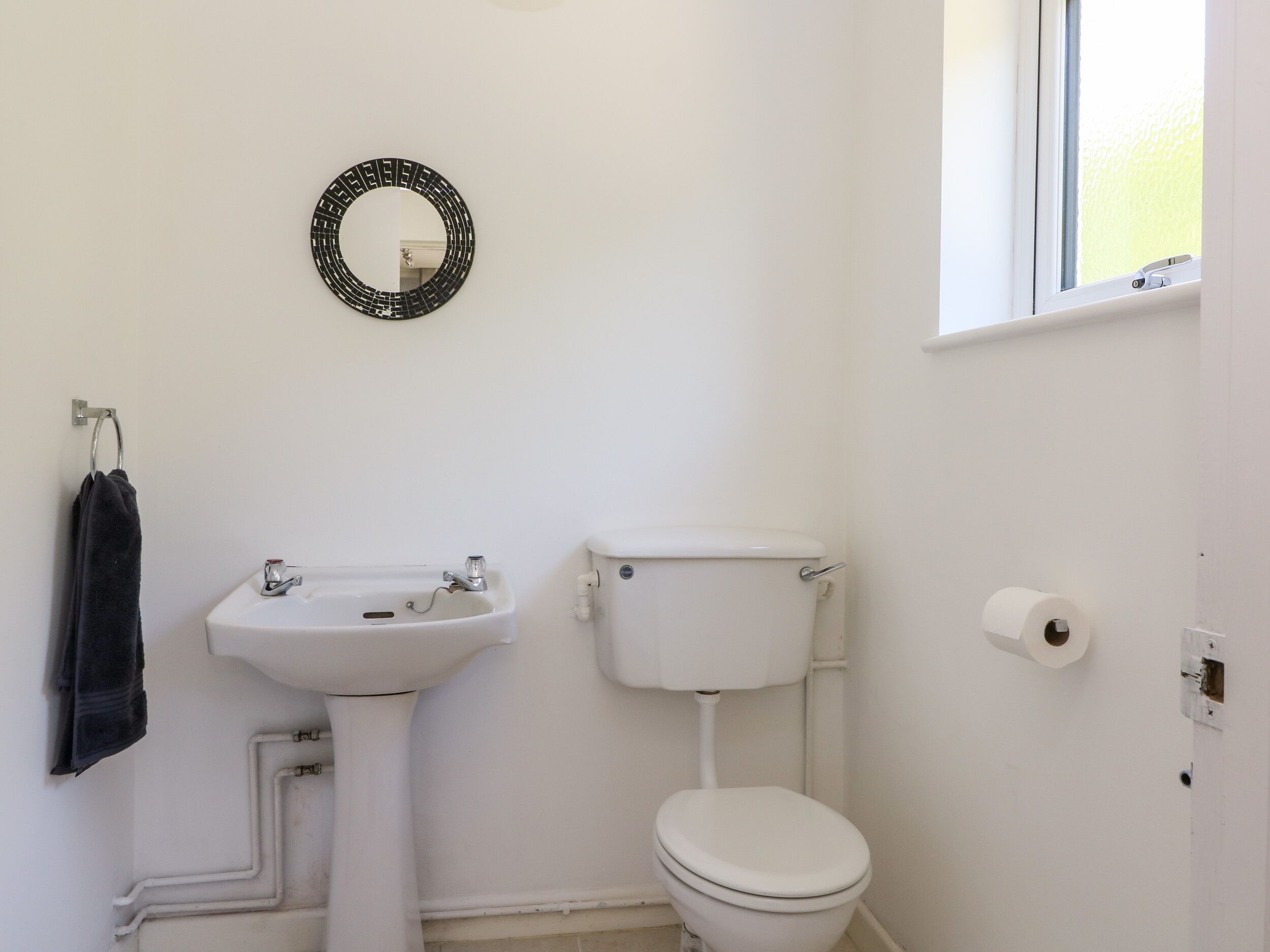 A bathroom with a white sink, toilet, and a mirror on the wall.