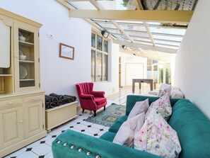 Une pièce avec un canapé vert, un fauteuil rouge, un meuble et un tapis à motifs.