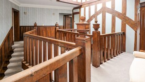 Una escalera de madera con barandilla, peldaños alfombrados y un candelabro.