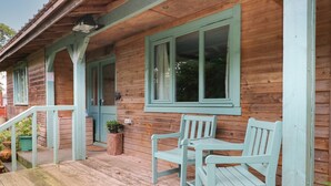 Ein Holzhaus mit Veranda, zwei Bänken und einem Blumentopf.