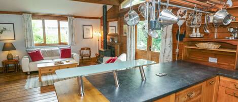 A cozy cabin with a wooden interior, a dining table, and a kitchen area with hanging utensils.