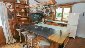 Eine Küche mit Kochinsel, Barhocker, Holzschränken und einem Kühlschrank.