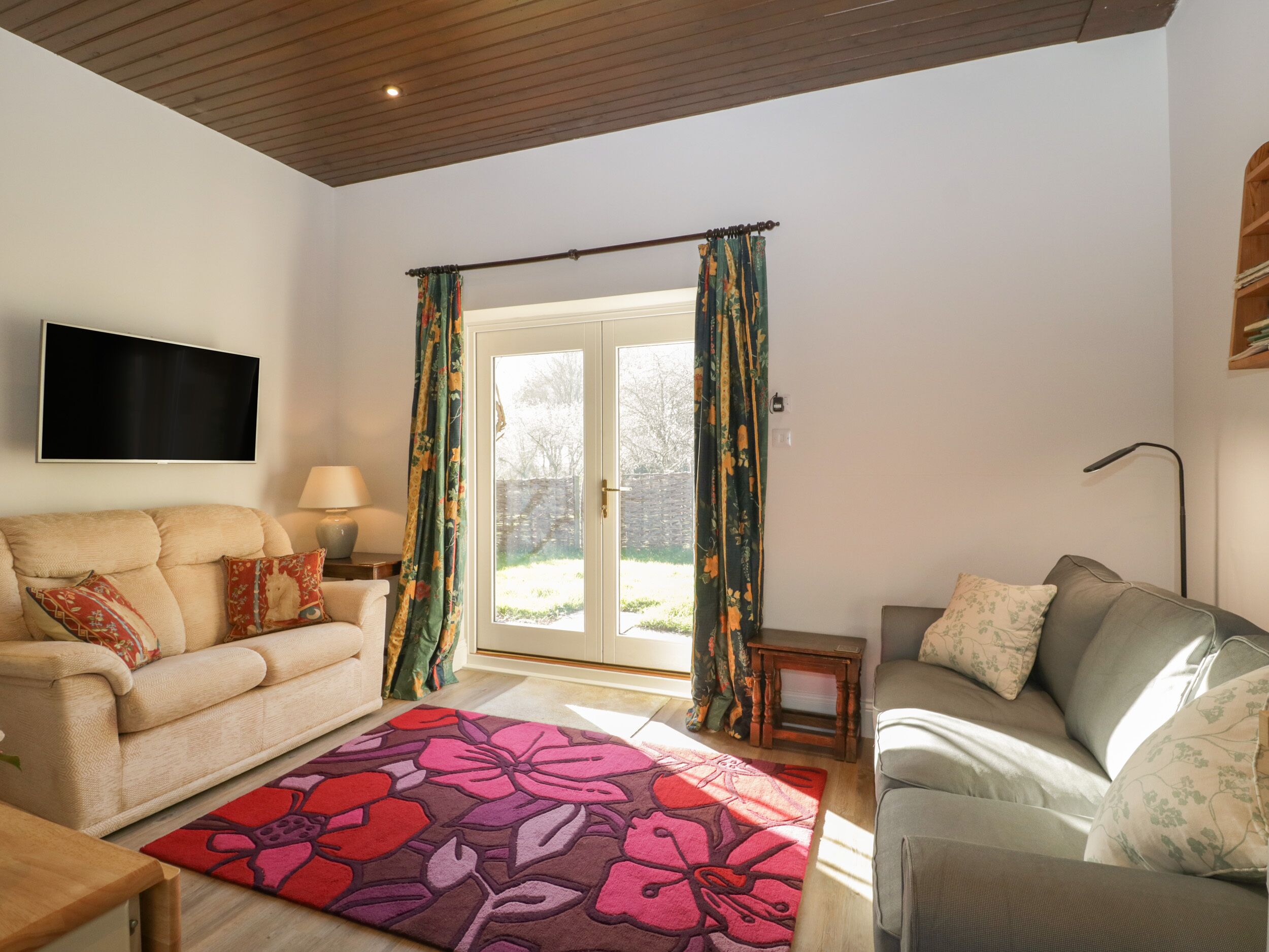 A living room with two sofas, a flat-screen TV, a lamp, and a patterned rug.