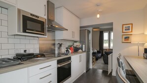 Eine moderne Küche mit weißen Schränken, Edelstahlgeräten und einem Essbereich mit Tisch und Stühlen.