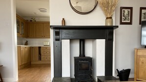 A modern kitchen with wooden cabinets, a black fireplace, and a mirror on the wall. - Auverne (Bude)