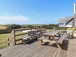 A wooden deck with picnic tables and chairs, overlooking a rural landscape. - Auverne (Bude)
