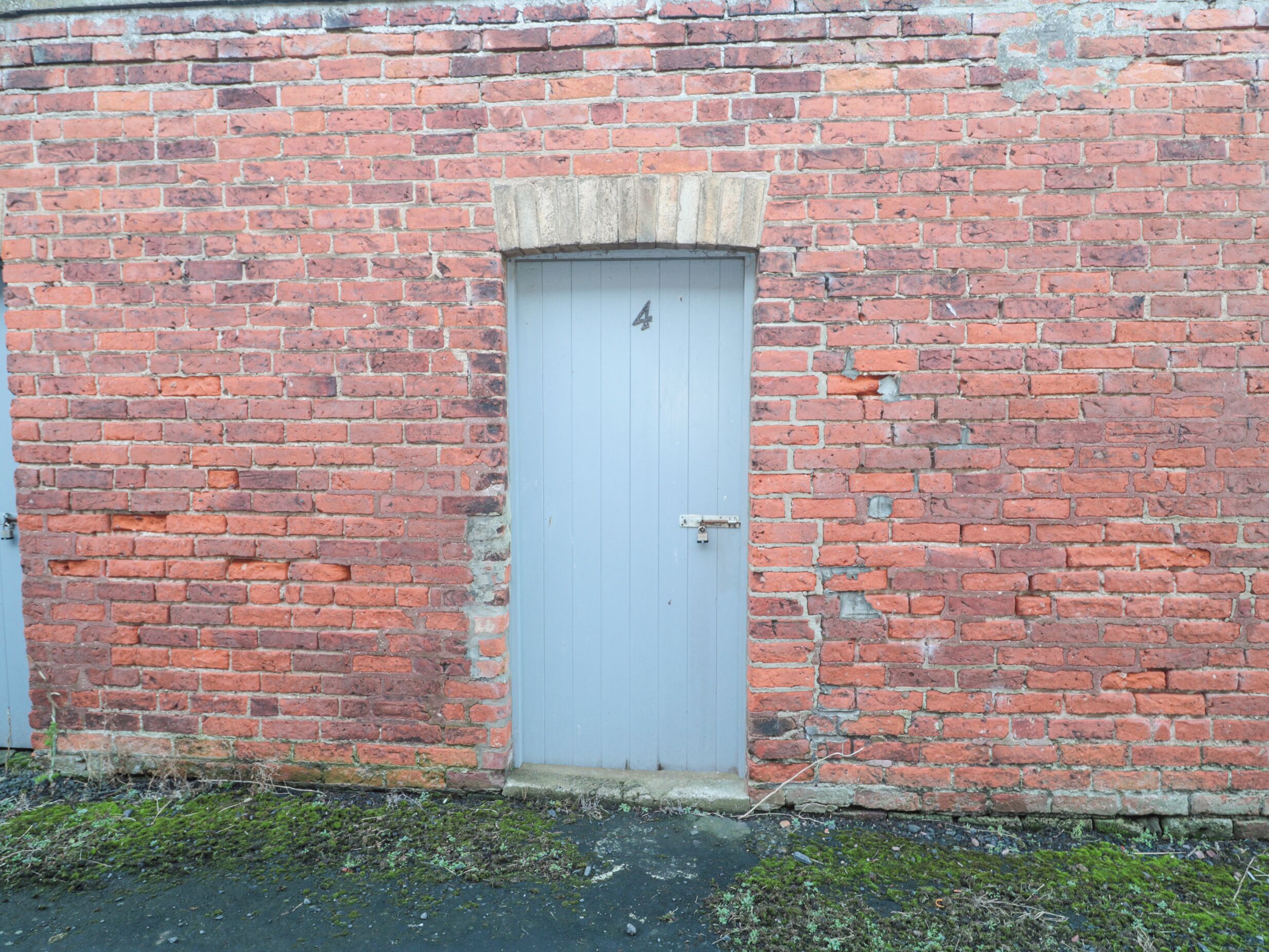 A red brick building with a white door and a small window above it.