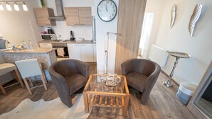 A modern kitchen with wooden cabinets, a built-in microwave, and a clock on the wall. - Ferienwohnung Anke - Appartement 5 (Heinsberg)