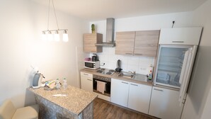 A modern kitchen with a granite countertop, stainless steel appliances, and light wood cabinetry. - Ferienwohnung Anke - Appartement 5 (Heinsberg)