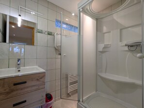A bathroom with a glass-enclosed shower, a sink with a mirror, and a wooden vanity.