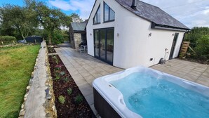 Et moderne hus med swimmingpool, stenskikkede stier og en terrasse med udendørs møbler.