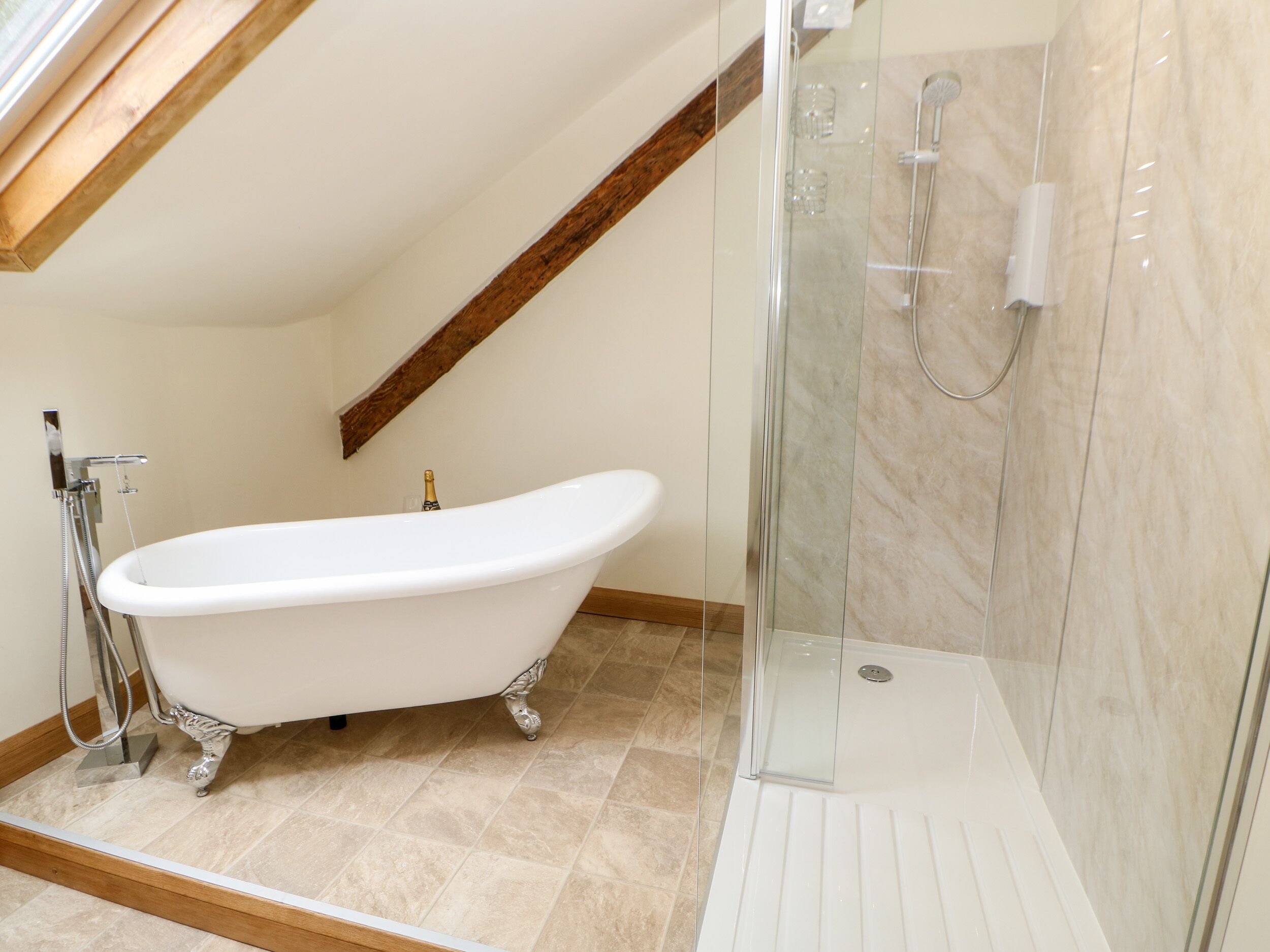 A bathroom with a freestanding bathtub, a glass-enclosed shower, and a wooden beam ceiling.